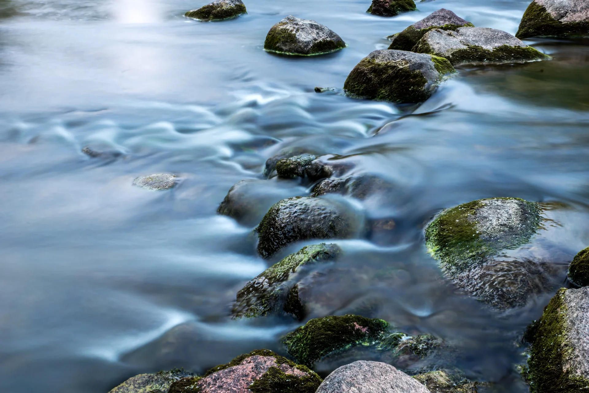 A scene of river rocks with water on top of them.
